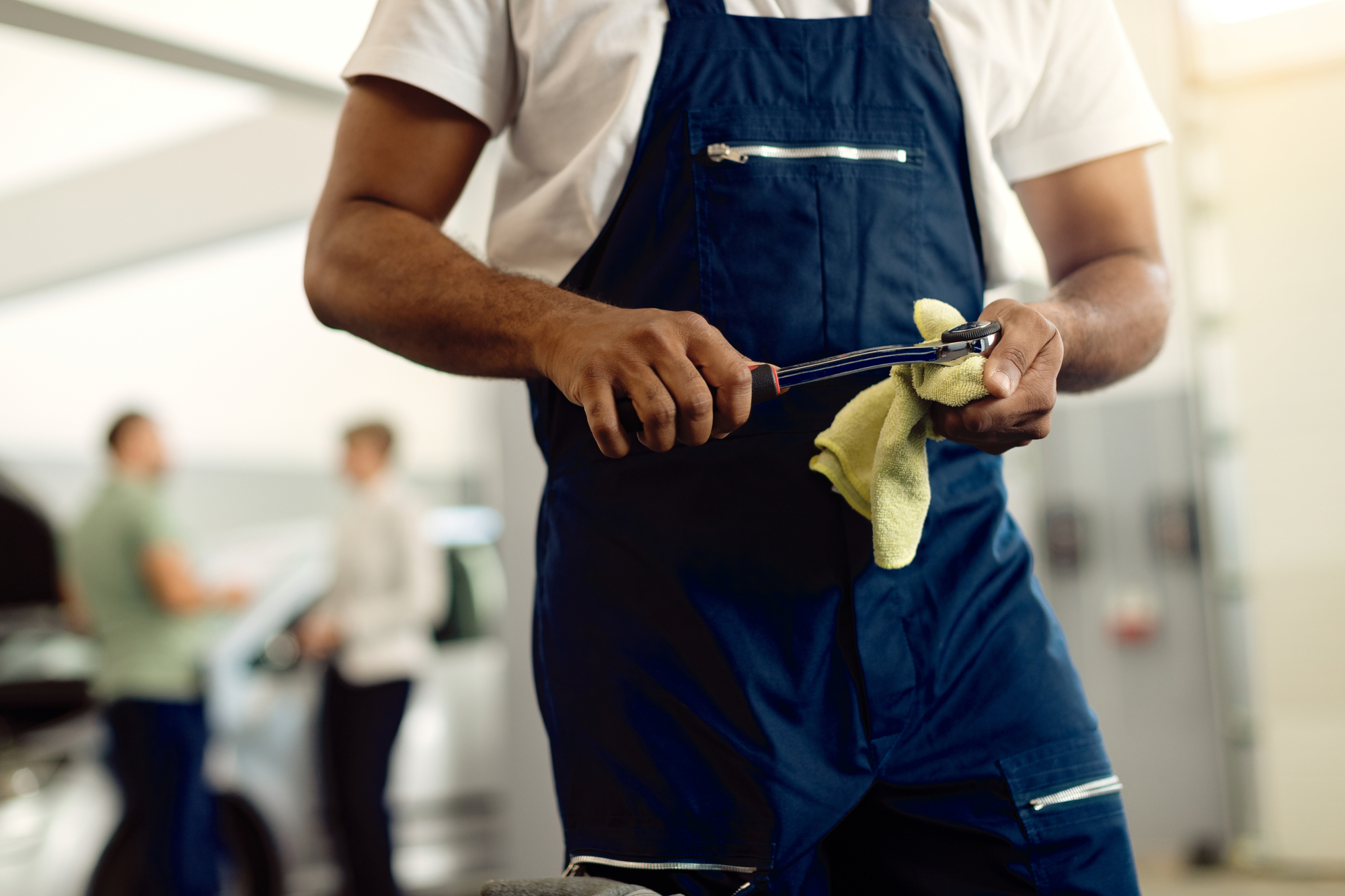 Unrecognizable repairman using wrench while working at car servi